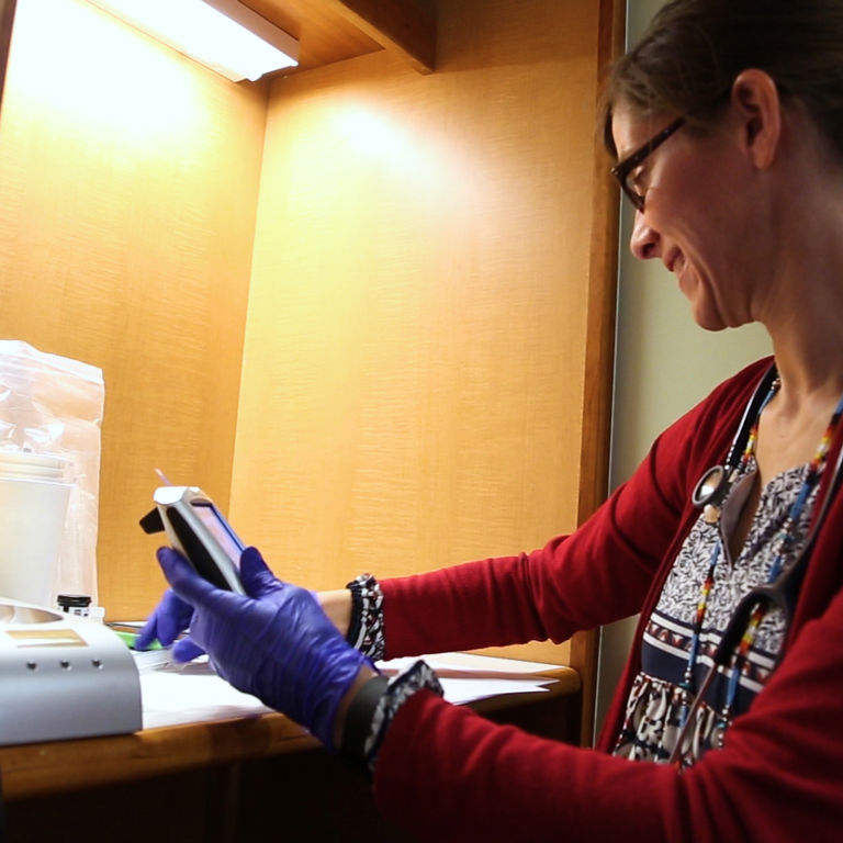 Doctor Kristen Nadeau, Children's Hospital Colorado, wears blue gloves while handling a medical device.