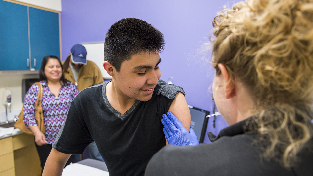 A teenage boy gets a shot at the child health clinic.