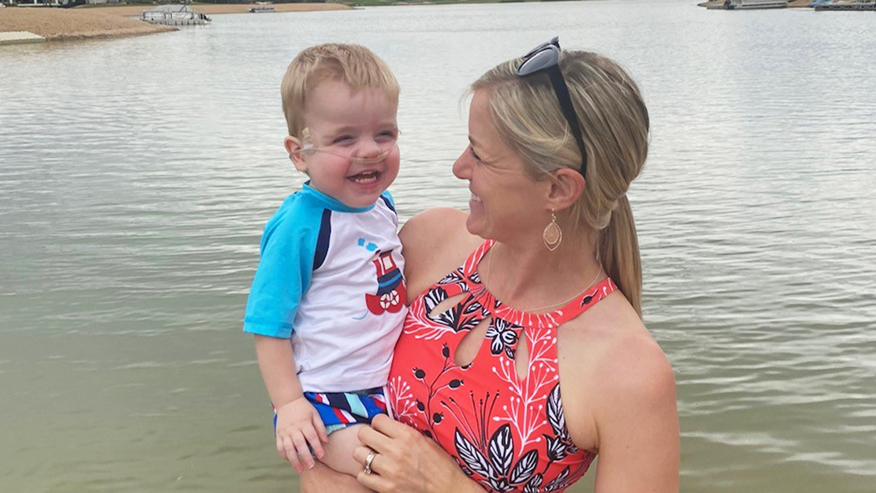 Young toddler with oxygen smiling while being held by mother