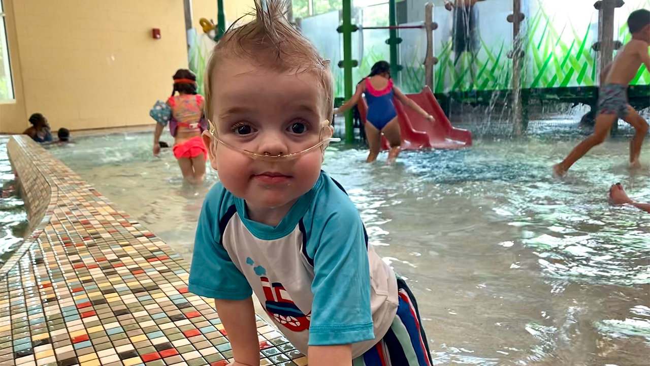 Young toddler with oxygen playing in indoor pool