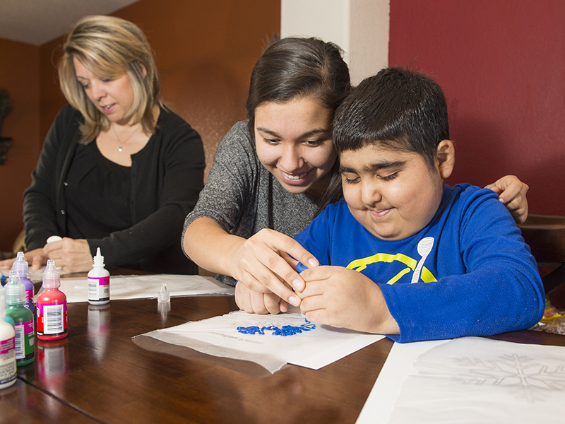 Cole Chavez, former patient of the Center for Cancer and Blood Disorders at Children's Hospital Colorado, colors with help from his family.