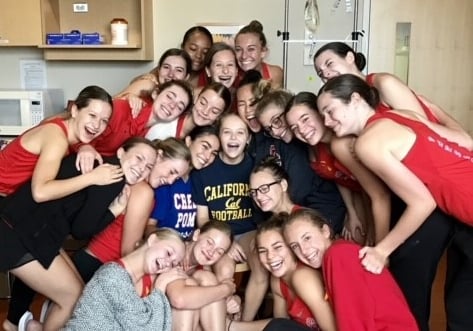 A girl and her dance team smiling in her hospital room