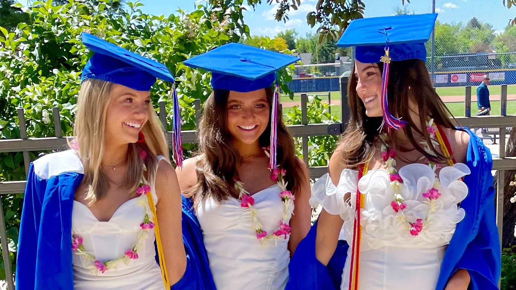 Three girls smiling in graduation caps and gowns