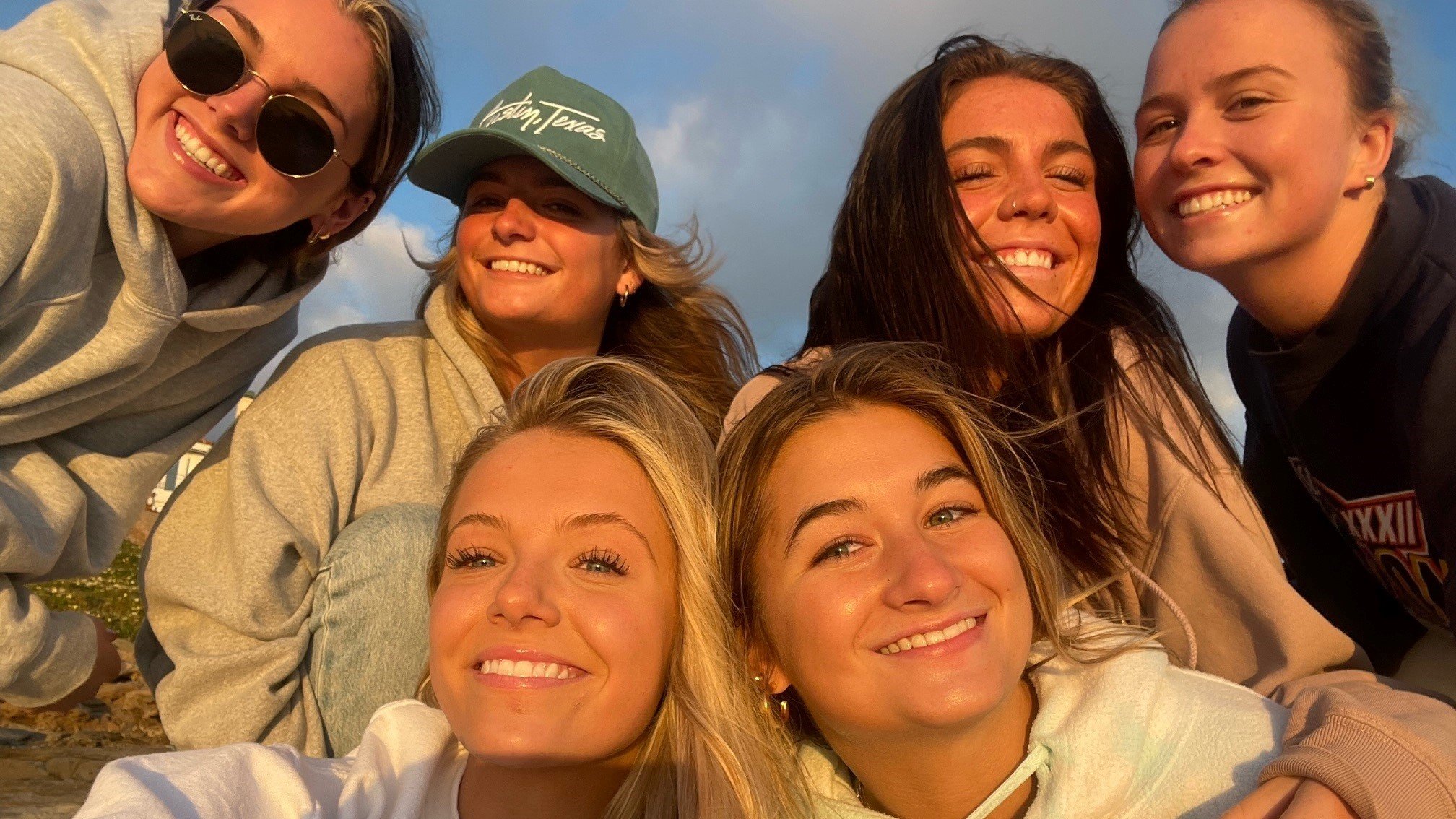 Six girls smiling on the beach at sunset