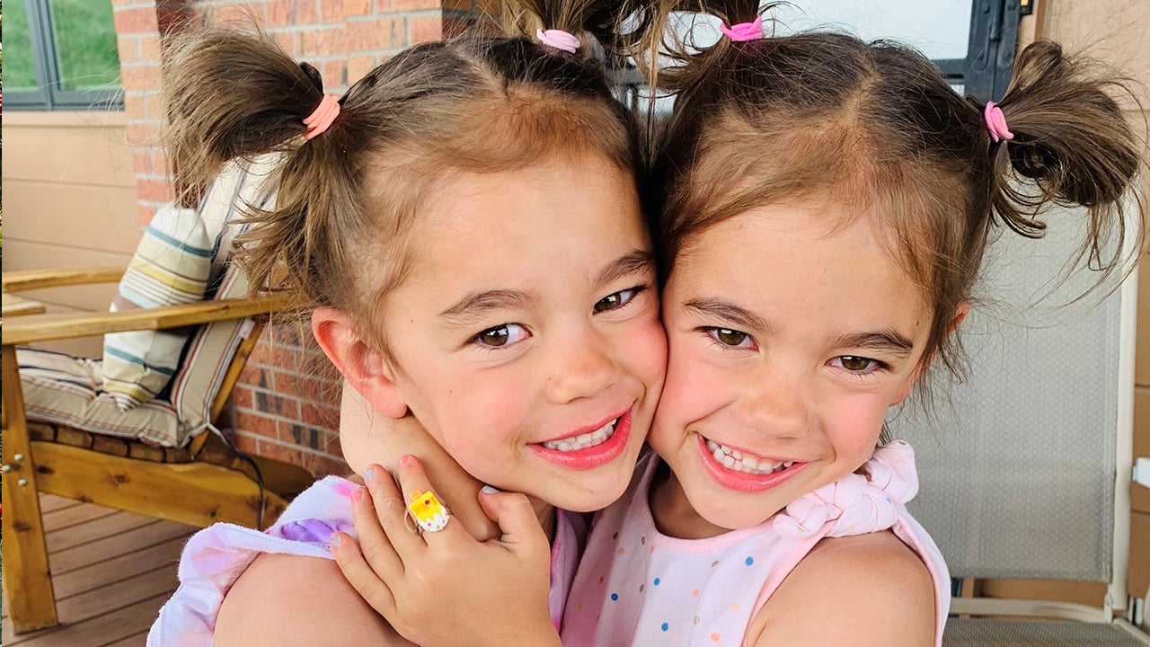 Five-year-old Kenna and Zoey smile and hug tightly. 