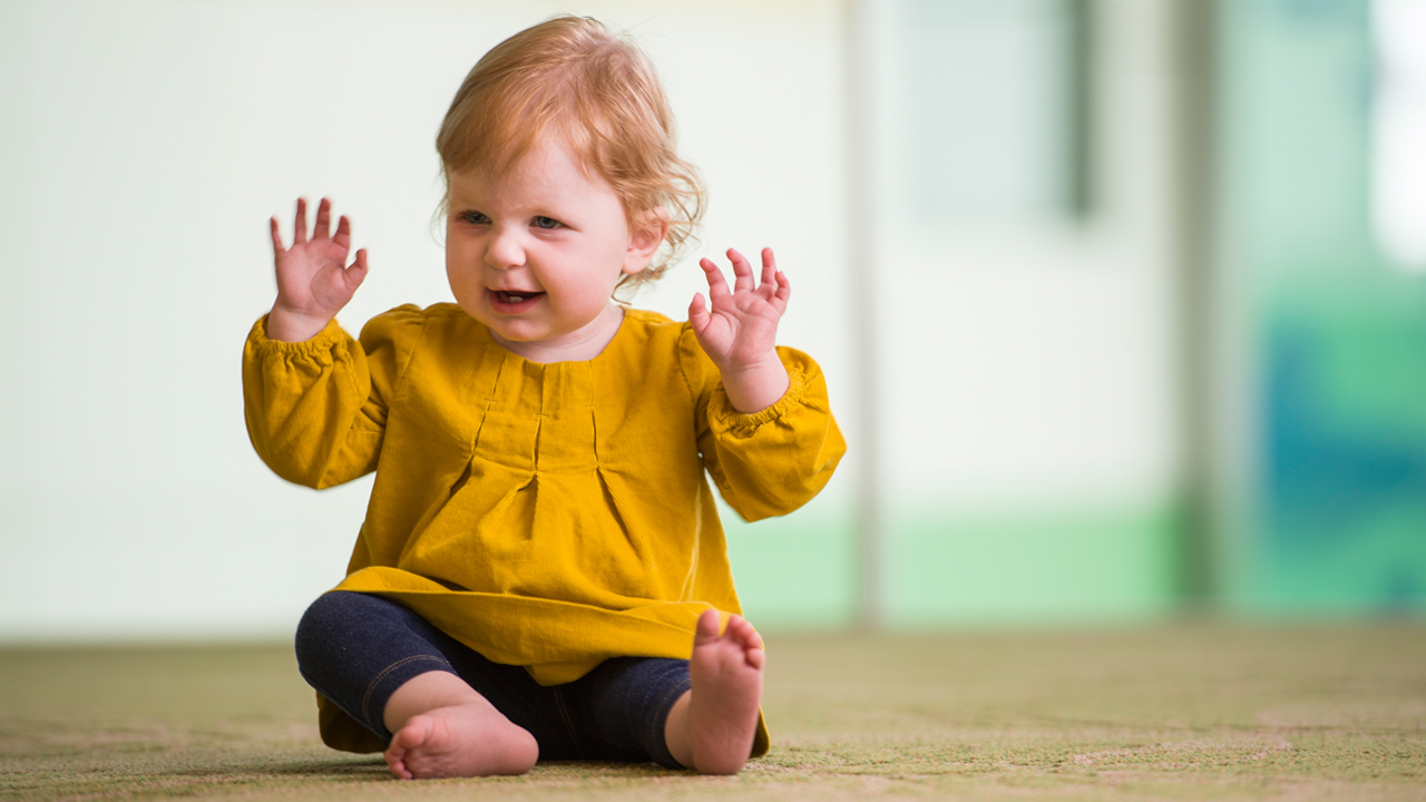 Juniper "Junebug" Gelrod, Children's Hospital Colorado's Youngest Ever Recipient of the Berlin Heart, sits on the floor happily.