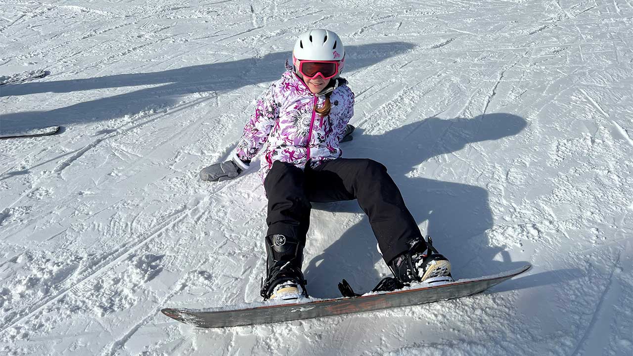 Kendall sits on a run while snowboarding.