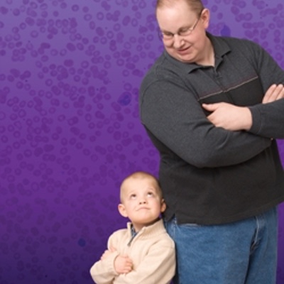 Kevin and Ethan, leukemia cancer survivors who were treated at Children's Hospital Colorado, stand back to back in front of a purple wall.