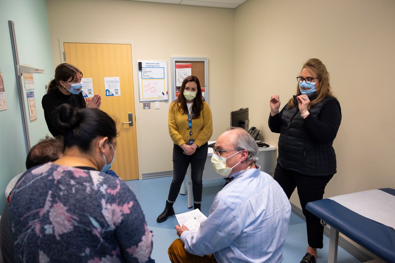 Medical interpreters, the physician and family all communicate together in an exam room.