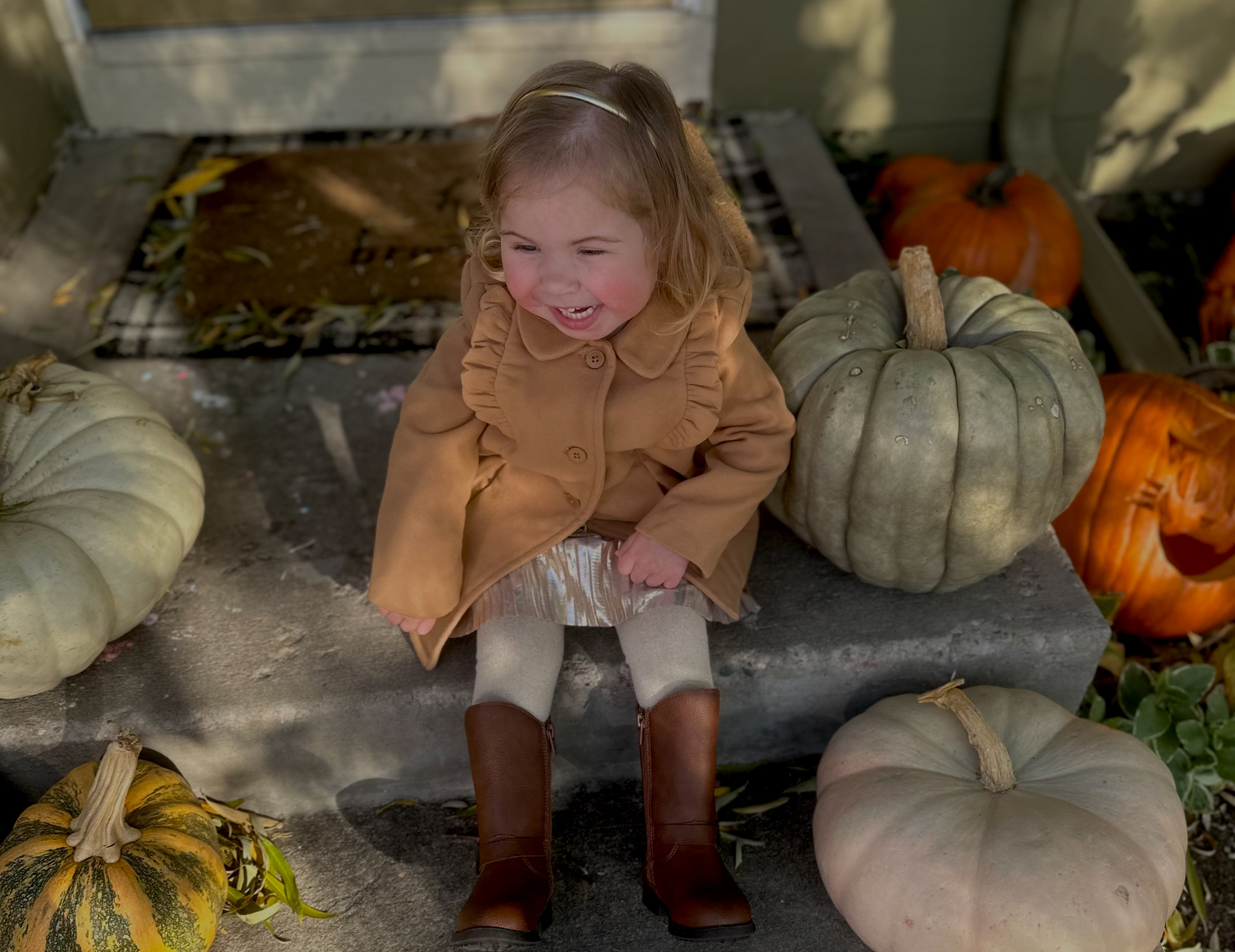 Willow sitting on a doorstep and smiling while surrounded by pumpkins