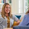 Lora sits on a couch talking to another mom about how Children's Hospital Colorado allowed her to be involved in the tonsillectomy process for her daughters.