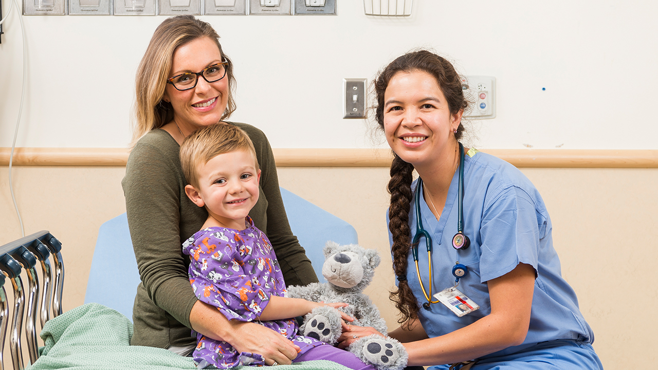 Picture of a patient and mother sitting on a hospital bed speaking with an anesthesiologist