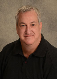 A headshot of heart chief perfusionist Scott Lawson who has short gray hair and is wearing a black polo.