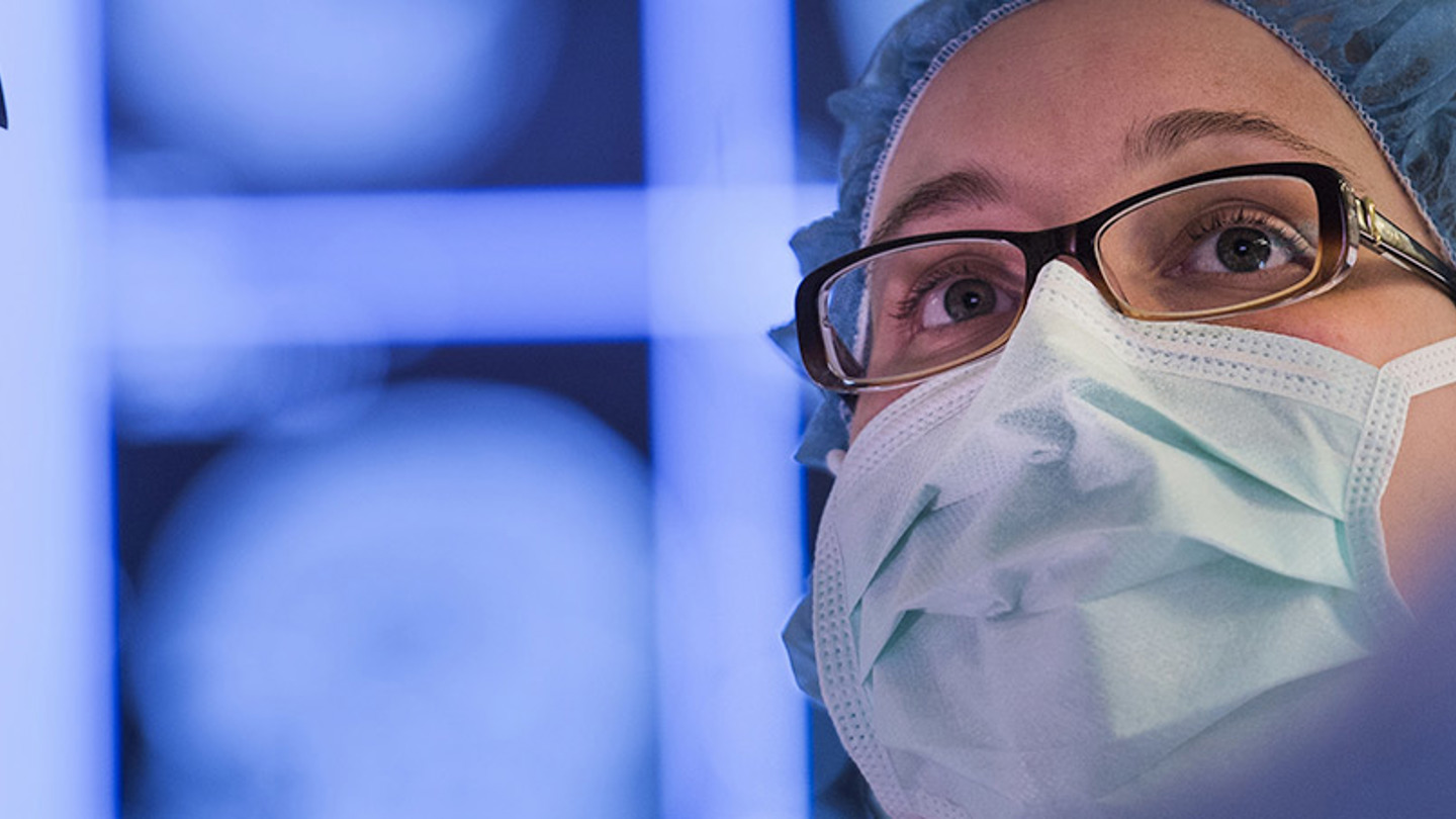 Close-up view of a doctor wearing glasses, a surgical head covering and surgical mask