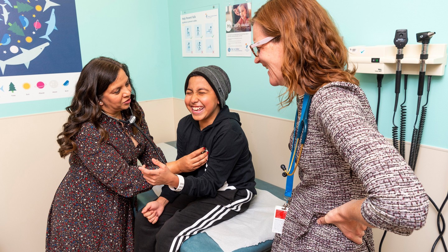 Two female providers examine an adolescent patient.