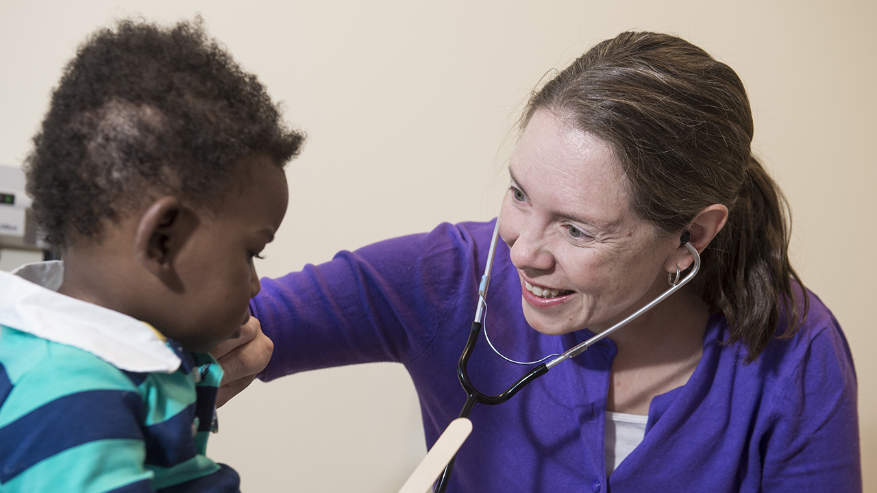 A doctor listens to a boy's heart