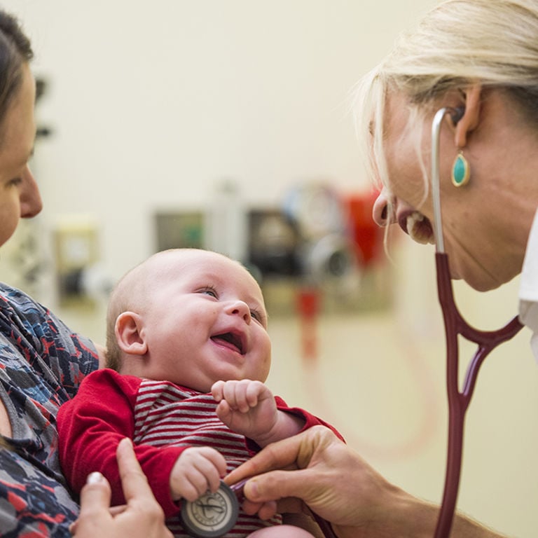 A doctor listens to a baby's heart