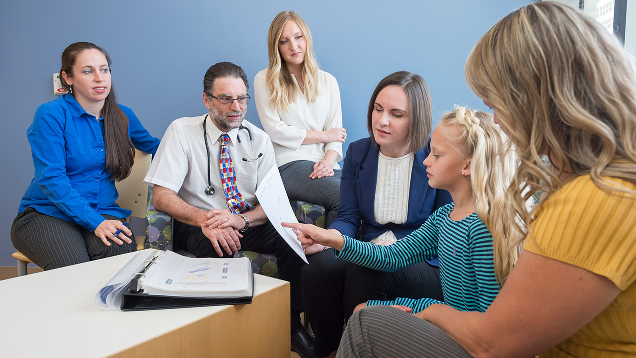 (From left) Pediatric gastroenterologist Edward Hoffenberg, MD; genetic counselor Alexandra Suttman, MS, CGC; and pediatric oncologist Lindsey Hoffman, DO, talk genetics with a patient and her mom.