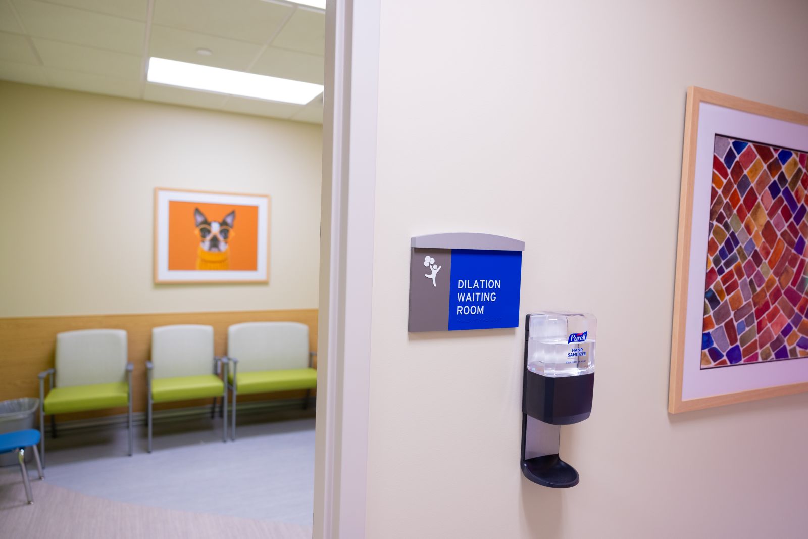 Entrance with a sign to dilation waiting room with rows of chairs in background 