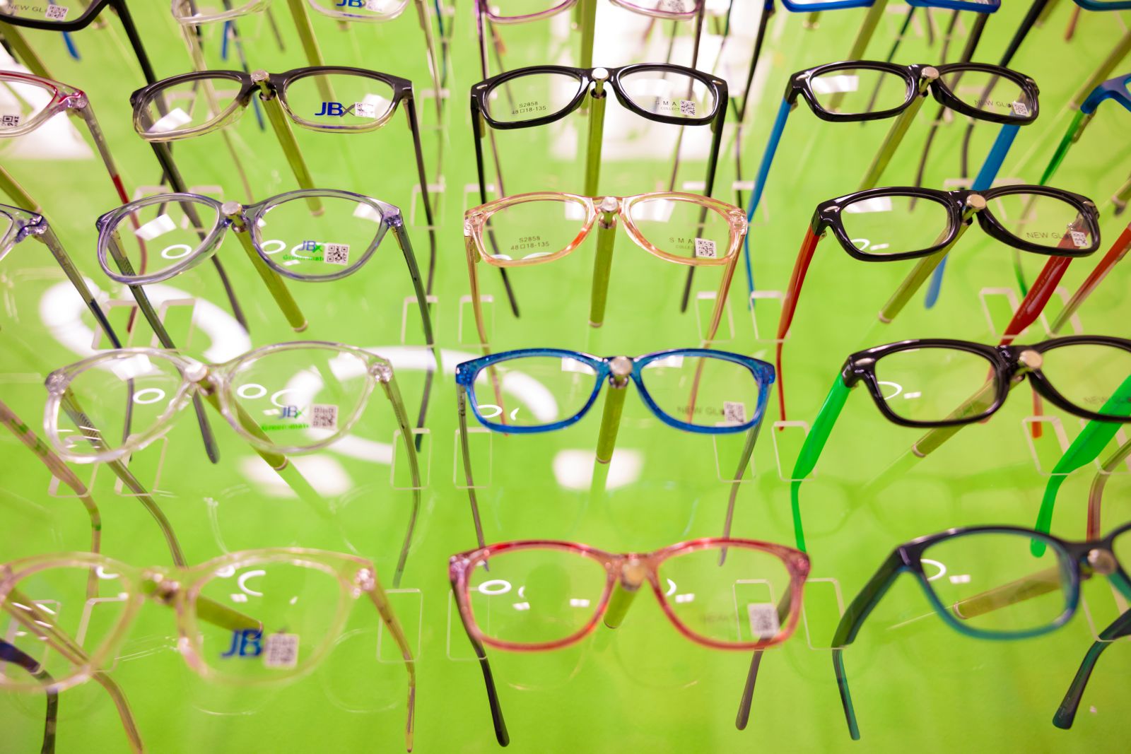 A green wall of rows of eyeglasses lined up.  