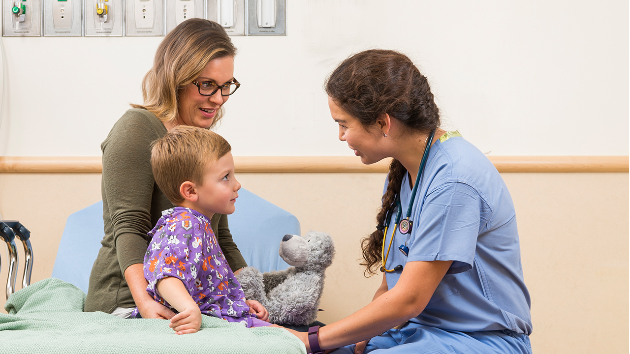 Anesthesiologist speaking to a patient and parent in an exam room