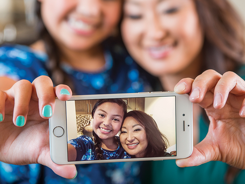 A mom and daughter take a selfie with a phone