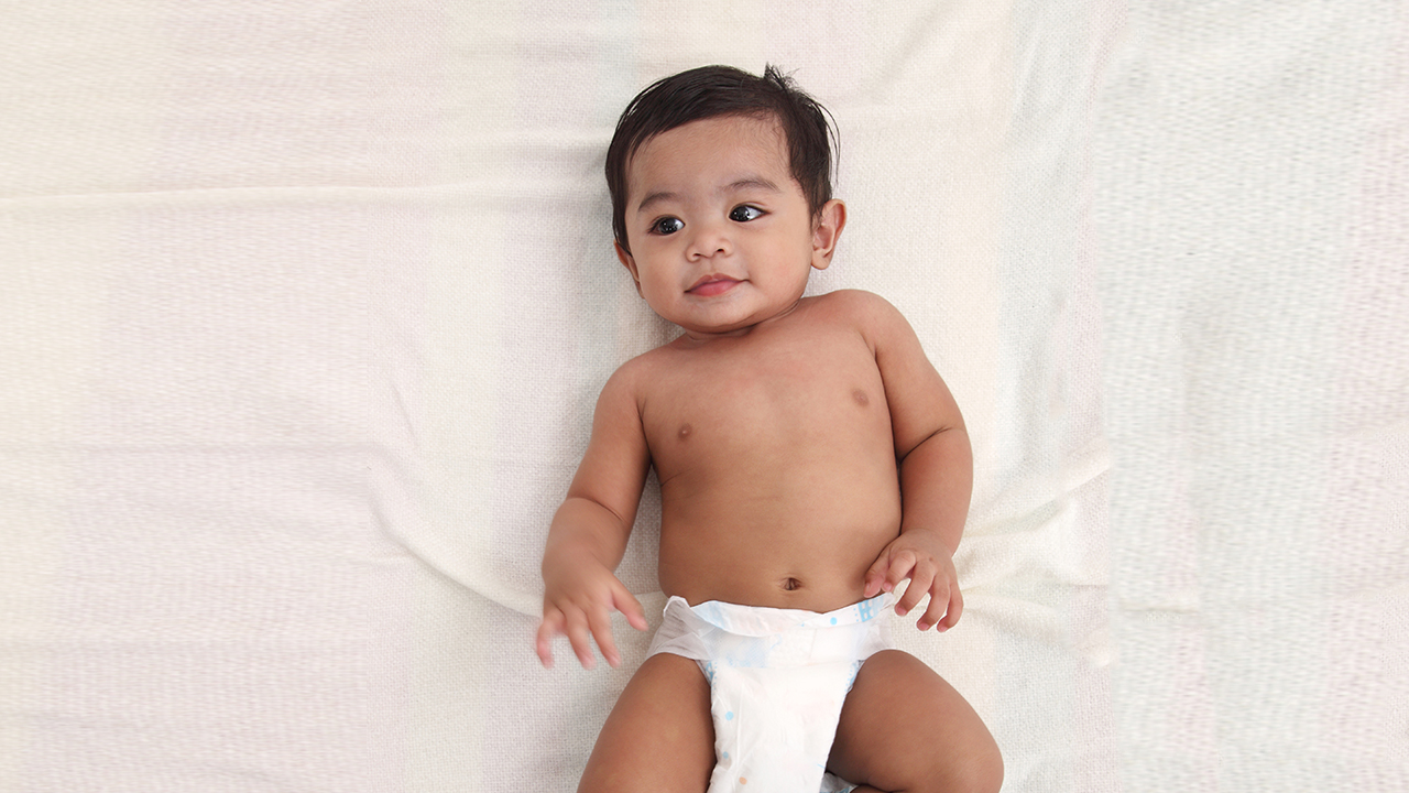 Baby laying down on white sheets.