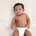 Baby laying down on white sheets.