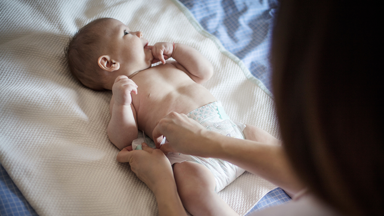 Baby boy having his diaper changed on a blanket.