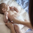 Baby boy having his diaper changed on a blanket.