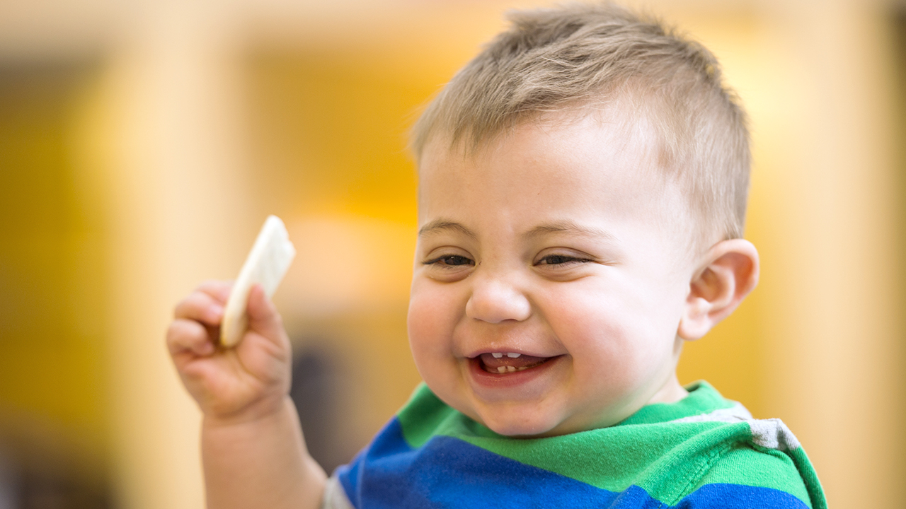 Smiling baby eating a cracker