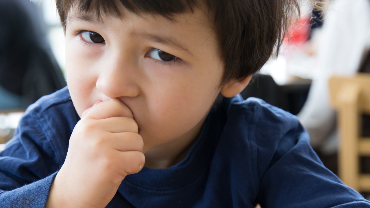 A young boy eats a peanut.