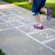 A child builds healthy bones by playing hopscotch on a sidewalk.