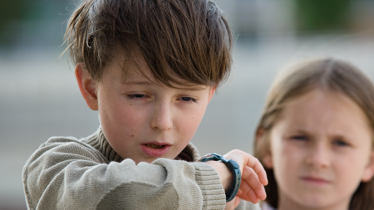 A boy coughs into his arm.