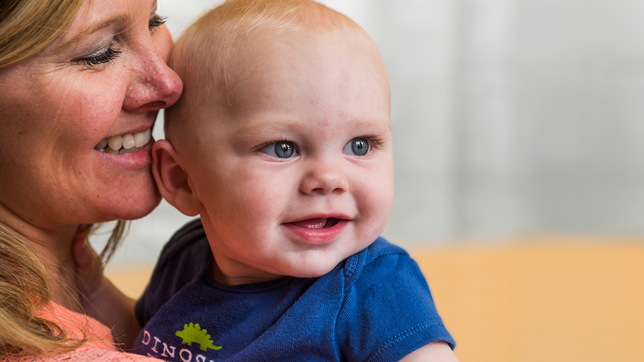 A smiling mom holds her baby close to her face.