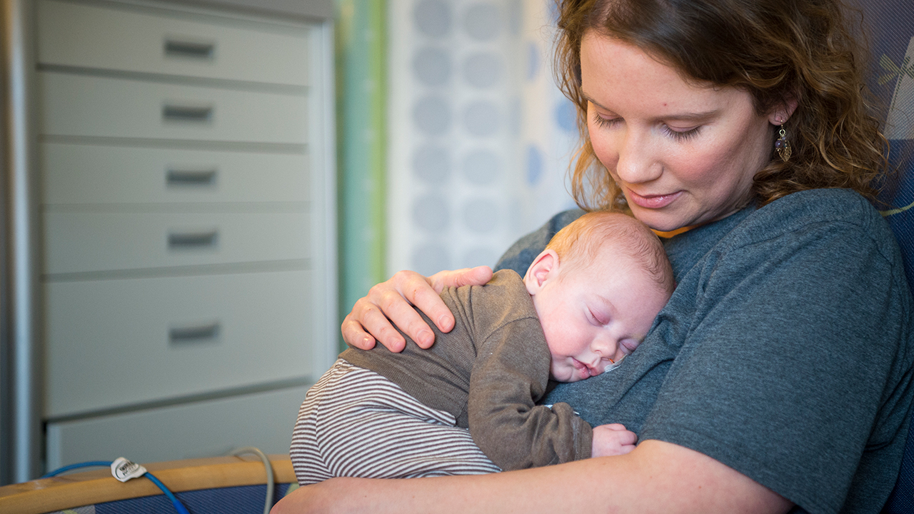 A baby boy sleeping on his mom’s chest in the Neonatal Intensive Care Unit.