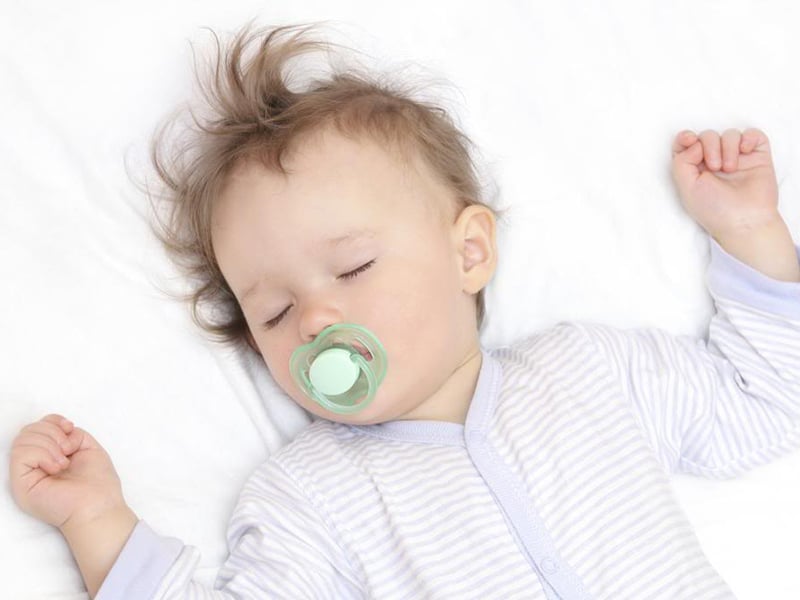 An infant sleeps on their back in a crib