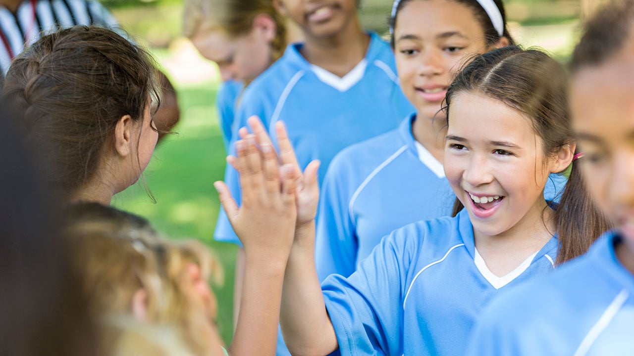 young girl high fives opponent at soccer game