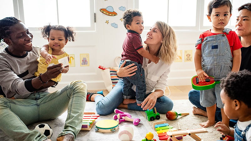 A group of adults and toddlers smiling and laughing with each other.