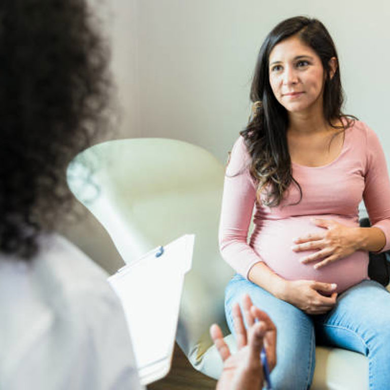 Pregnant woman sitting holding her belly