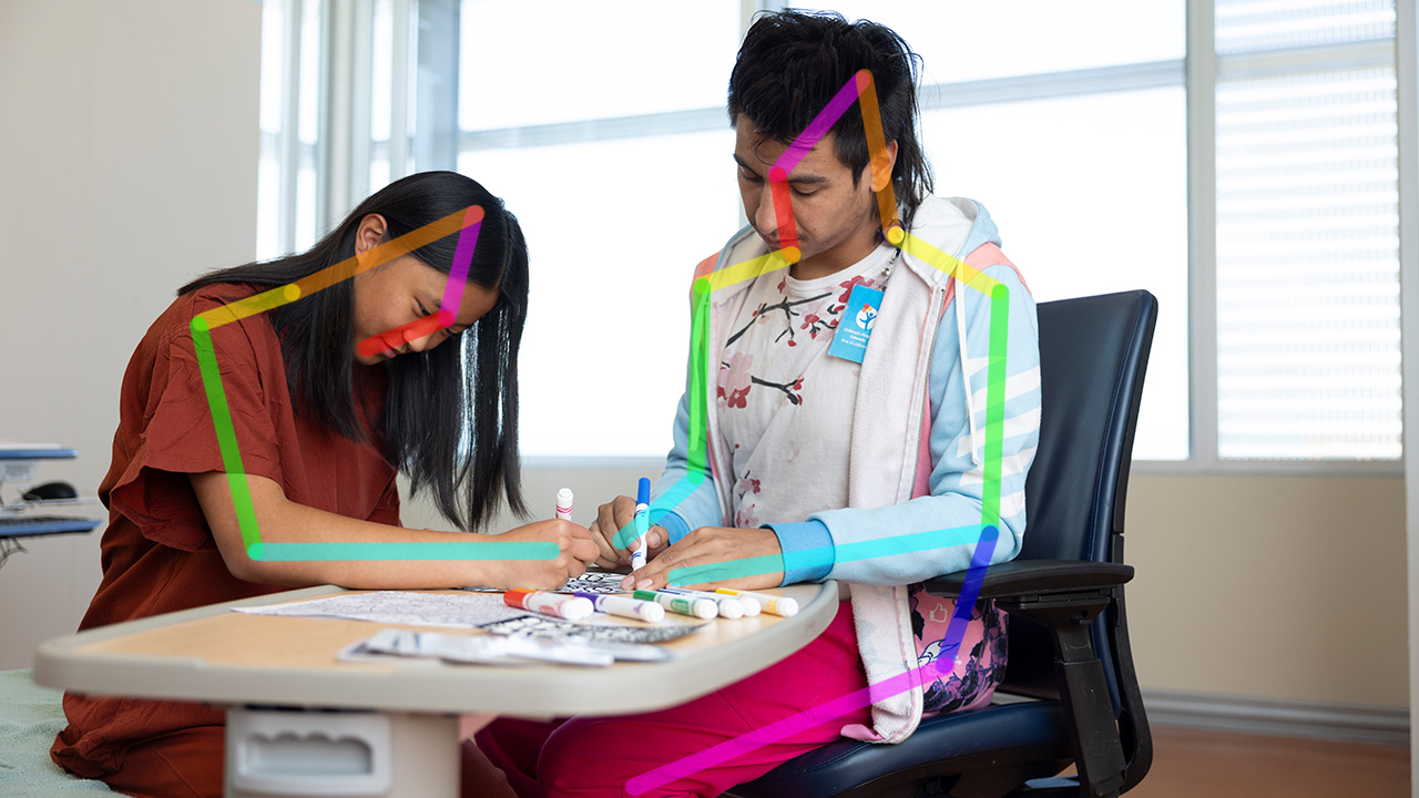 A provider and patient color with markers together. Multicolored lines are overlayed across their bodies.