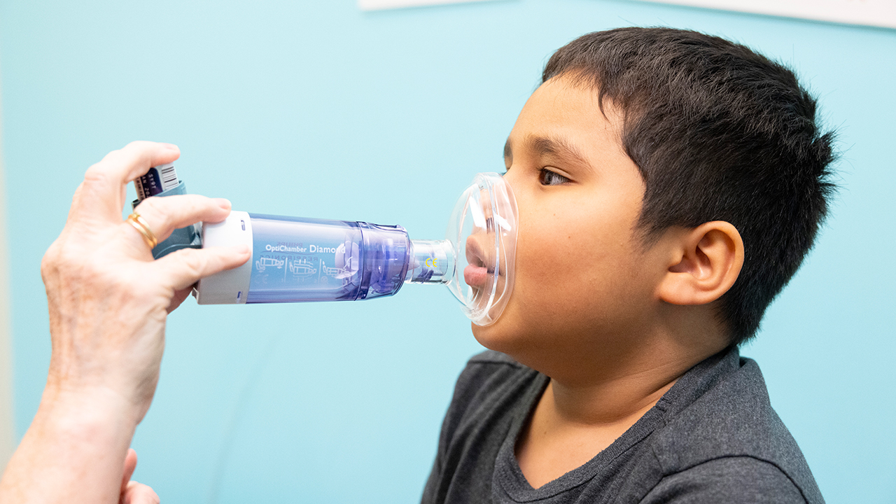 Young boy uses an albuterol inhaler