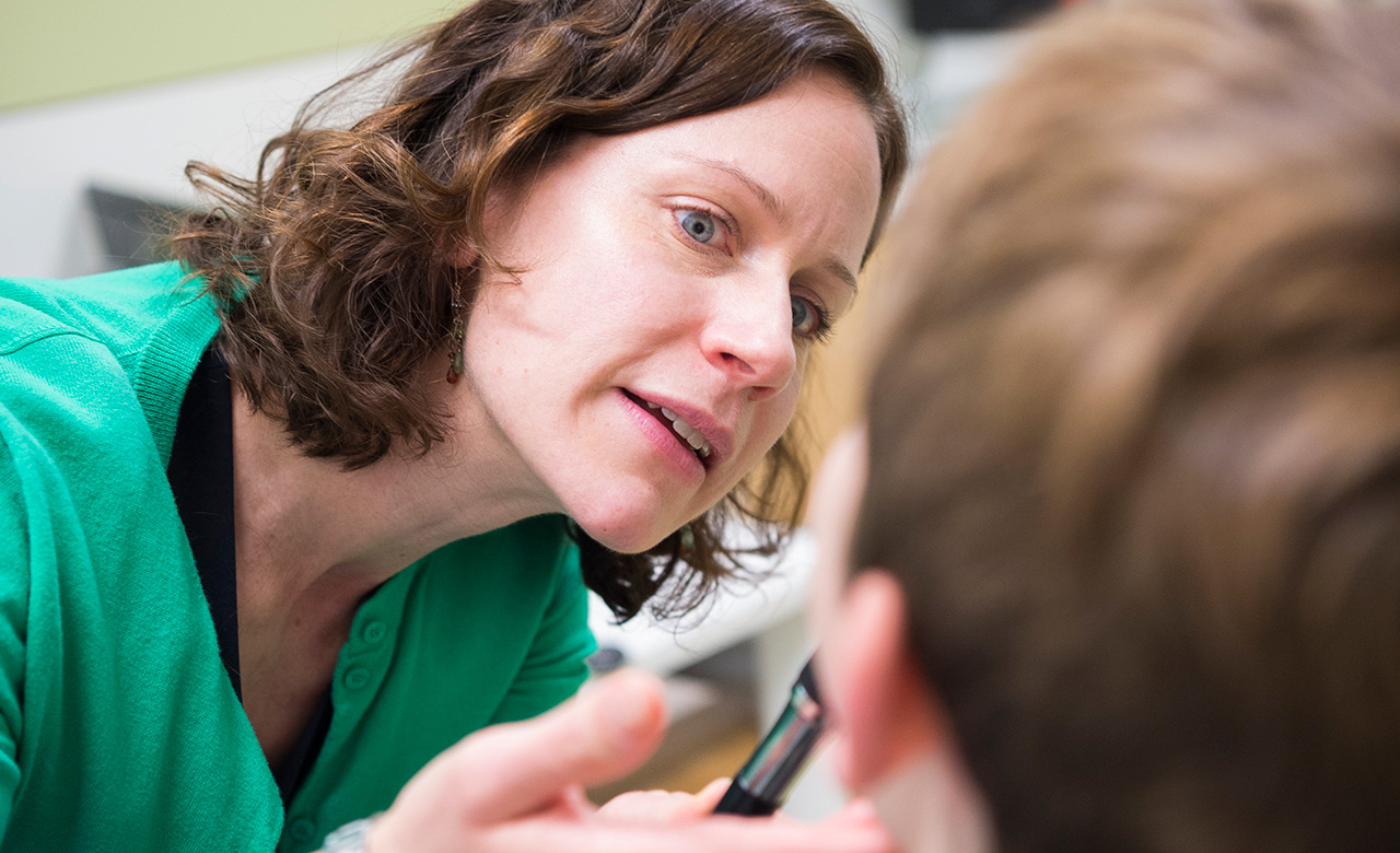 Calies Menard-Katcher, MD, assessing a patient in a clinic room