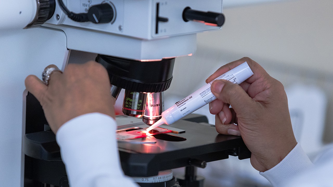 Person examines something under a microscope