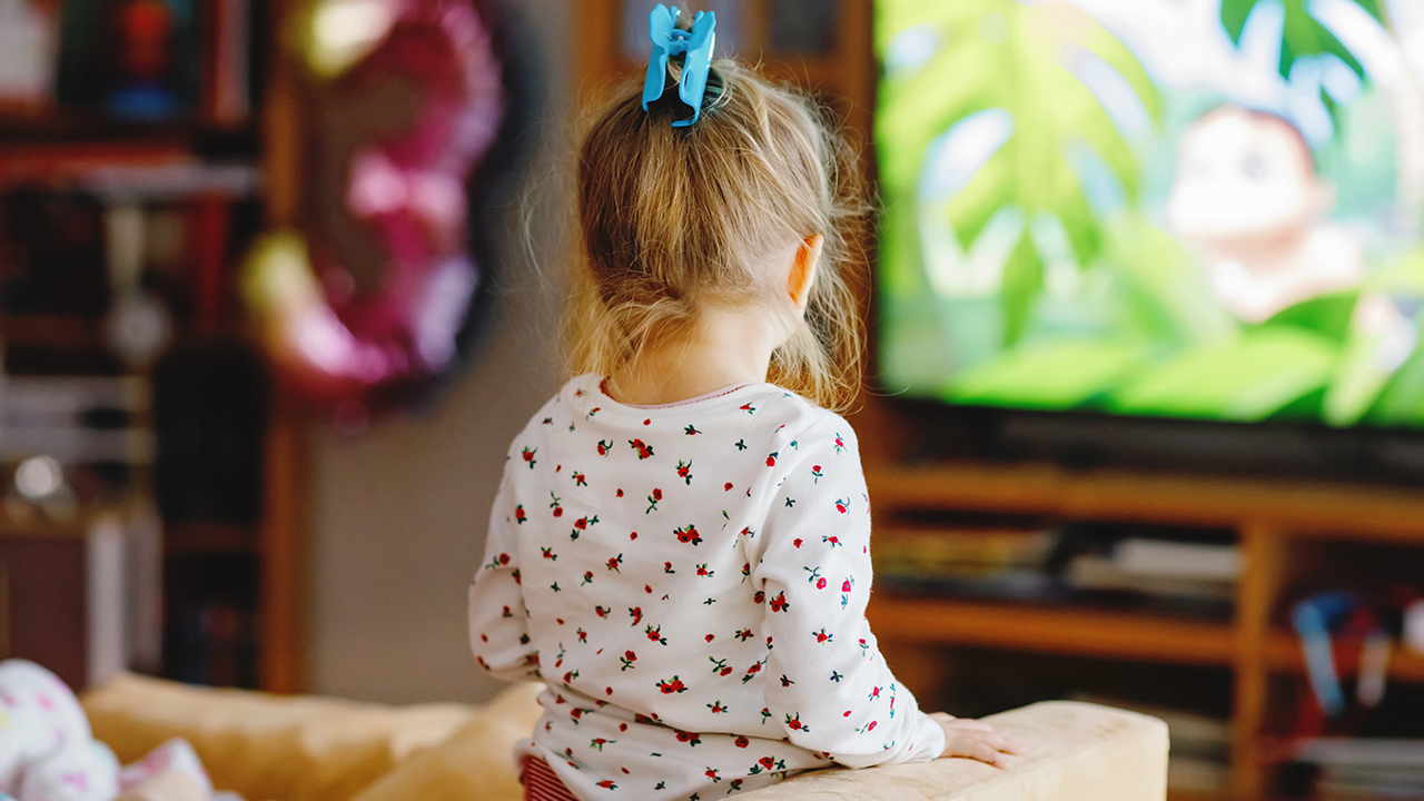 A child watching cartoons from the couch in a living room. 