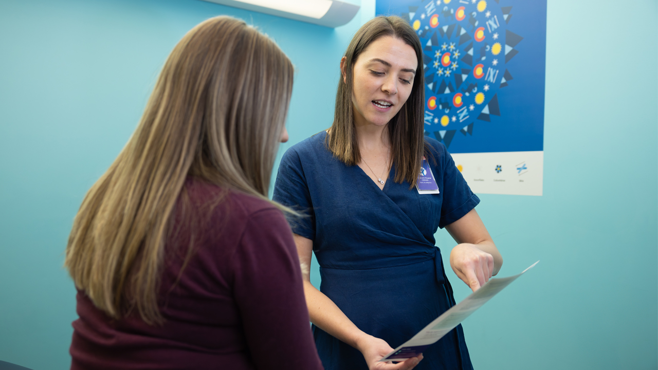 A provider at Children’s Colorado points at a piece of paper she’s holding while she explains IUDs to a female patient.