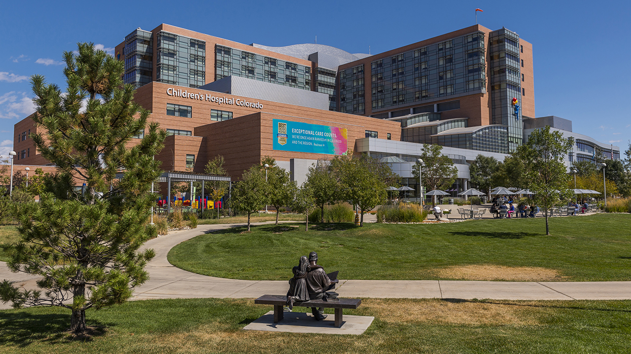 Children’s Hospital Colorado’s Anschutz Medical Campus location sits in front of a blue sky with a grassy field in front.