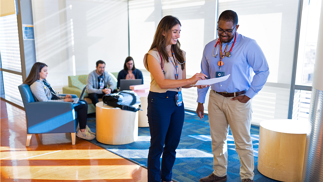 A smiling woman and a man look at a document together in the Children’s Colorado atrium.