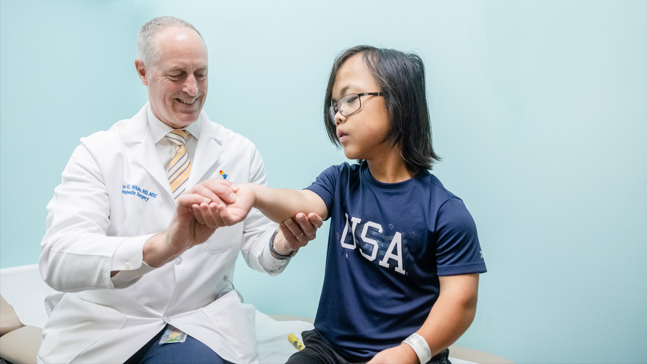 Dr. Klane White of Children’s Colorado examines a patient’s arm.