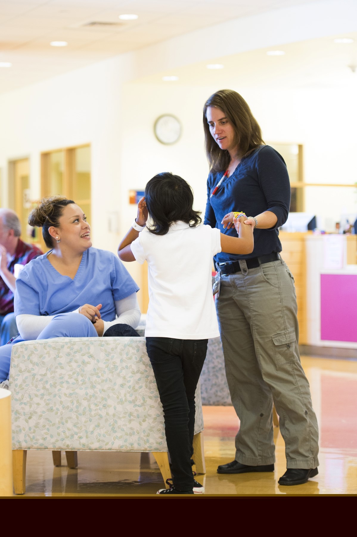 Dr. Jean Mulcahy-Levy helps a kid stand up while a woman in scrubs watches.